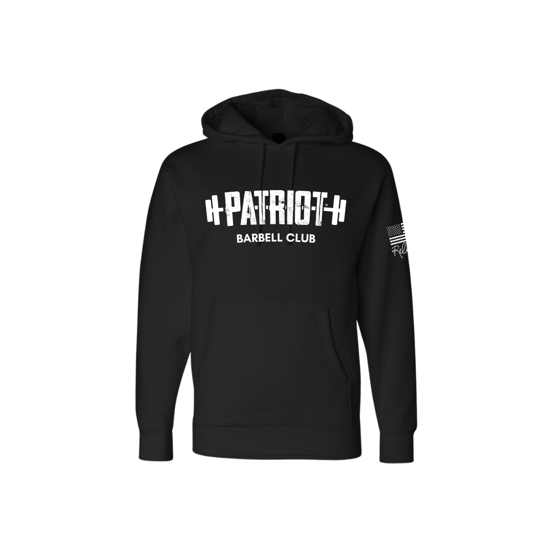 A solid black hooded sweatshirt featuring the words Patriot barbell club across the chest. The word PATROT is part of a barbell design. The barbell goes right through the letters, so that the weights are on either side. The sleeve has a distressed flag and Rebecca's signature underneath.