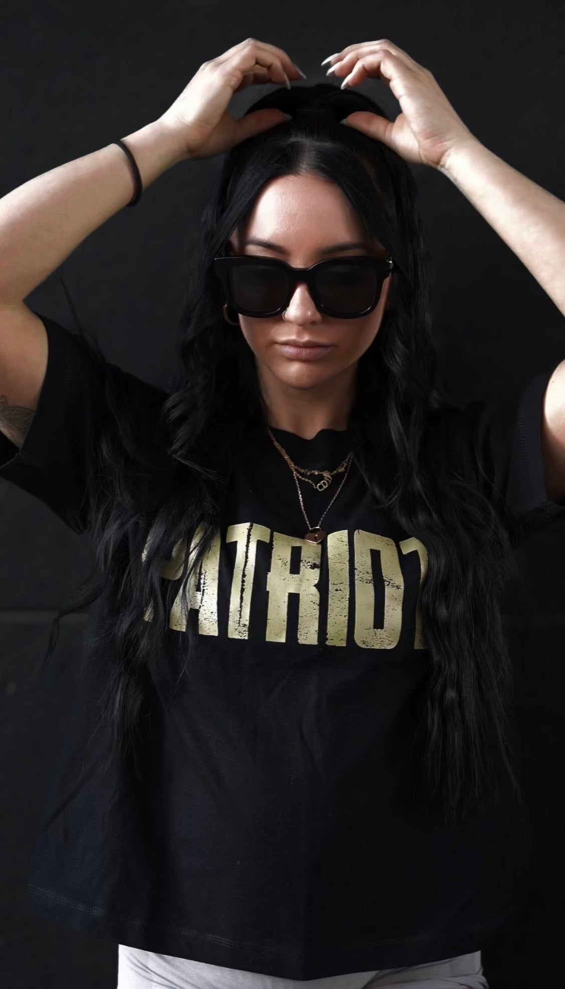 Marianna is wearing a black tee gold PATRIOT distressed logo on the chest.
