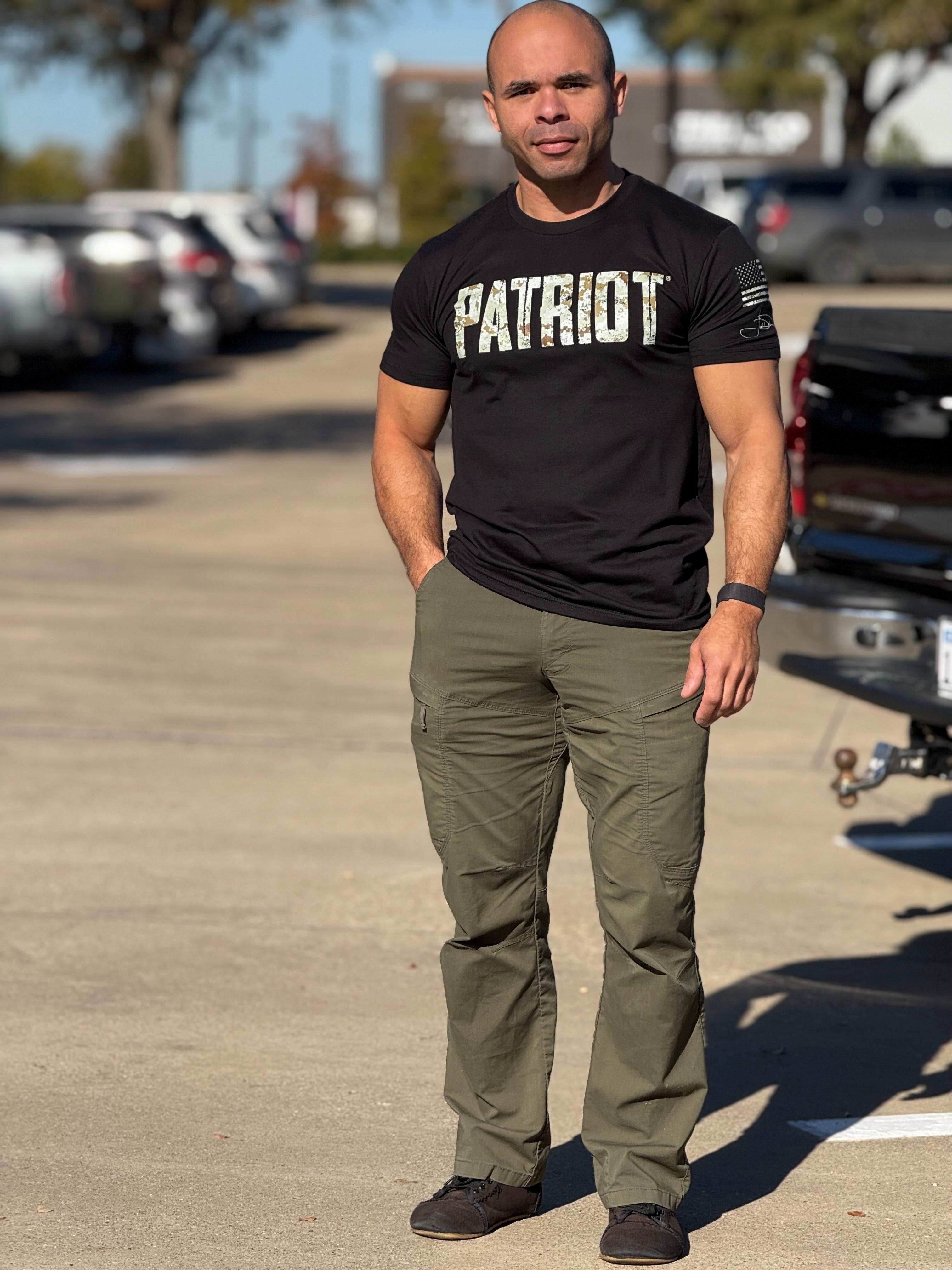 Joel, the Official Patriot who designed this shirt, stands proudly wearing his tee. He paired it with green cargo pants and black sneakers.