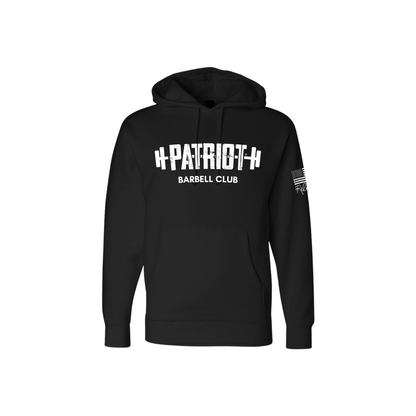 A solid black hooded sweatshirt featuring the words Patriot barbell club across the chest. The word PATROT is part of a barbell design. The barbell goes right through the letters, so that the weights are on either side. The sleeve has a distressed flag and Rebecca's signature underneath. 