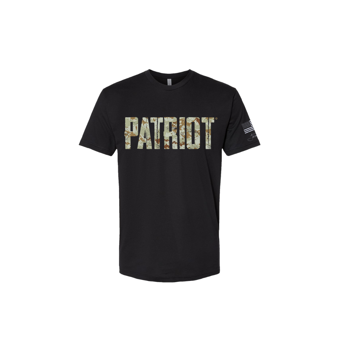 Black T shirt with the word PATRIOT across the chest in distressed letters that feature a green toned digital camo design throughout. The sleeve has a white distressed flag and Joel's signature underneath. 