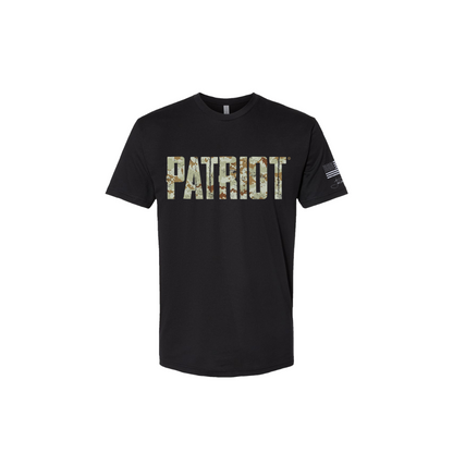 Black T shirt with the word PATRIOT across the chest in distressed letters that feature a green toned digital camo design throughout. The sleeve has a white distressed flag and Joel's signature underneath. 