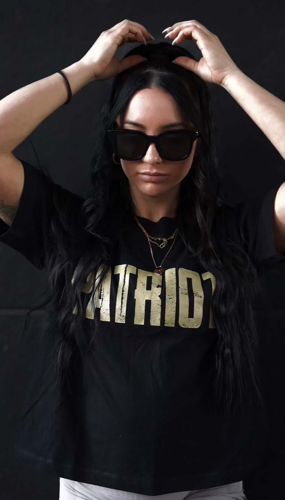 Marianna is wearing a black tee gold PATRIOT distressed logo on the chest. 